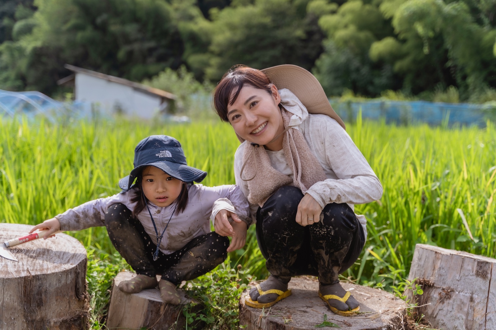 田んぼの切り株の上でガイドと子どもが笑っている